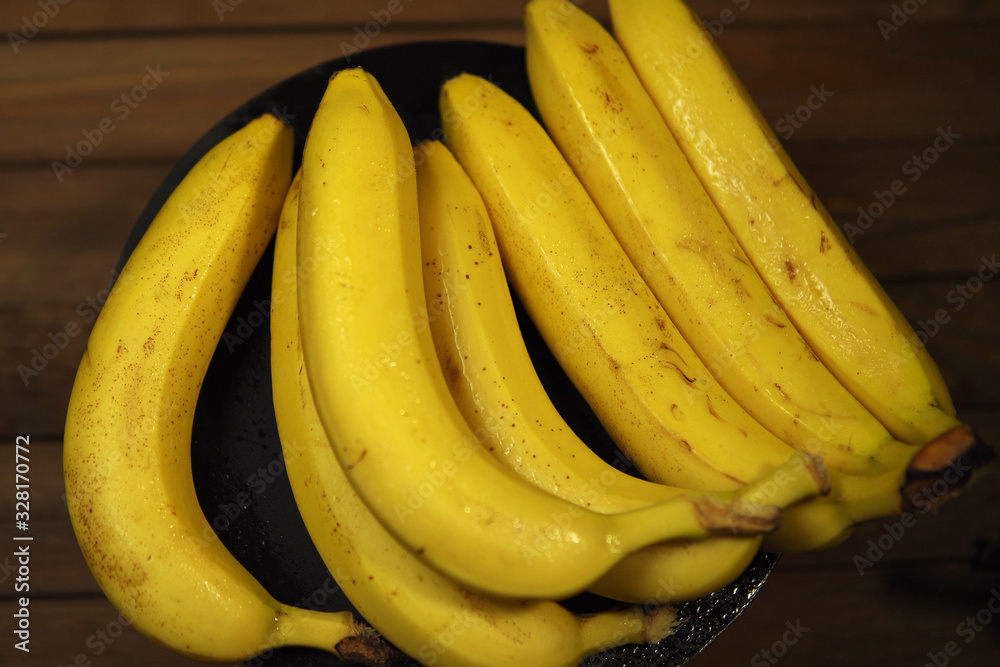 Ripe many wet bananas in black plate.