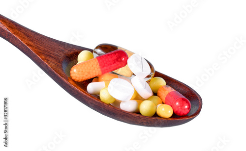 White Tablets In Wooden Spoon Against White Background