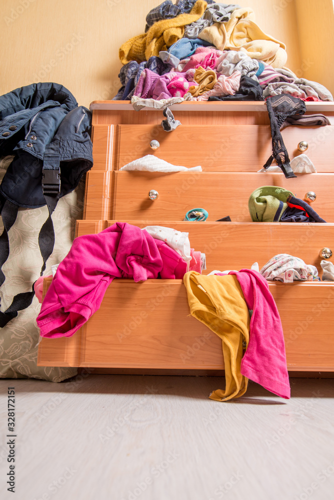 open chest drawers with drop-down clothes and piles of clothes around in a mess. Bottom view open chest drawers with drop-down clothes and piles of clothes around in a mess. Bottom view