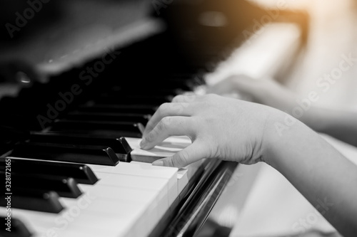 Selective focus to kid fingers and piano key to play the piano.