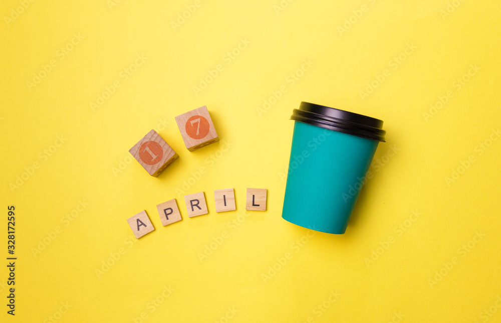 Simple flatlay design blue paper coffee Cup and date April 14 isolated on yellow colorful fashion background. World coffee day Simple flatlay design blue paper coffee Cup and date April 14 isolated on yellow colorful fashion background. World coffee day