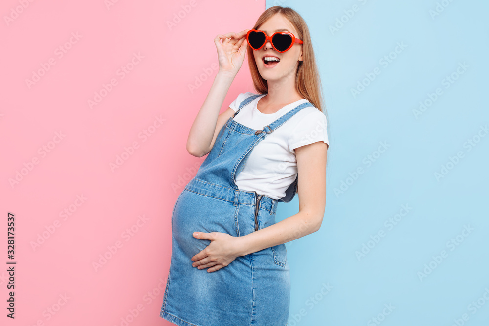 happy young pregnant woman in heart-shaped sunglasses