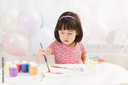 toddler girl practice watercolor paiting at home agianst white background photo