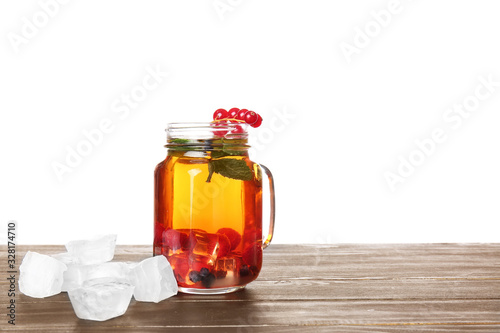 Mason jar of cold tea on table against white background