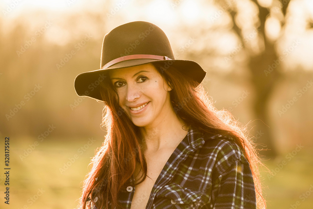 Ritratto di giovane donna sorridente con il cappello al tramonto in campagna  Stock Photo | Adobe Stock