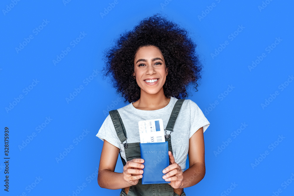 Tourism. girl wearing denim overall standing isolated on blue with passport and ticket laughing cheerful