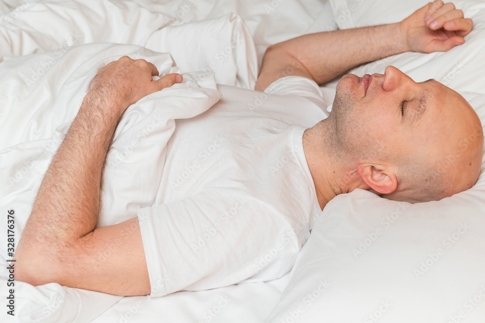 Bald man in white t shirt sleeps in a bed, Bald man in white t shirt sleeps in a bed,