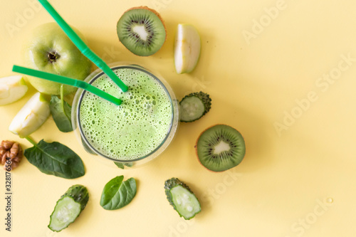 Fototapeta Naklejka Na Ścianę i Meble -  Dietary healthy green smoothie from cucumber, spinach, green apple and kiwi on a yellow background. Image with horizontal orientation and copy space. View from above