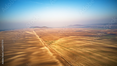 Aerial view of ploughed agricultural field. Dirt road through arable land Panorama