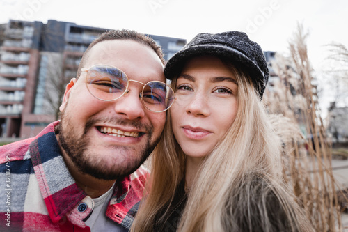 Two lovers making funny selfie, Portrait of cheerful laughing funny young people. Cute couple of hipsters is walking in spring park. Emotion facial expression. Beautiful sunny day. © mdyn