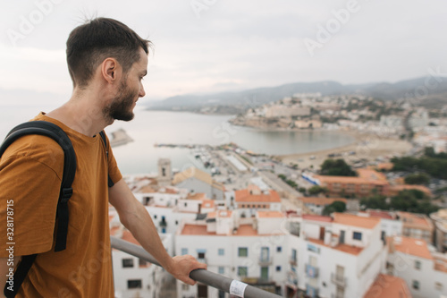 young male traveler stands on top of castle, city view, Peniscola Spain photo