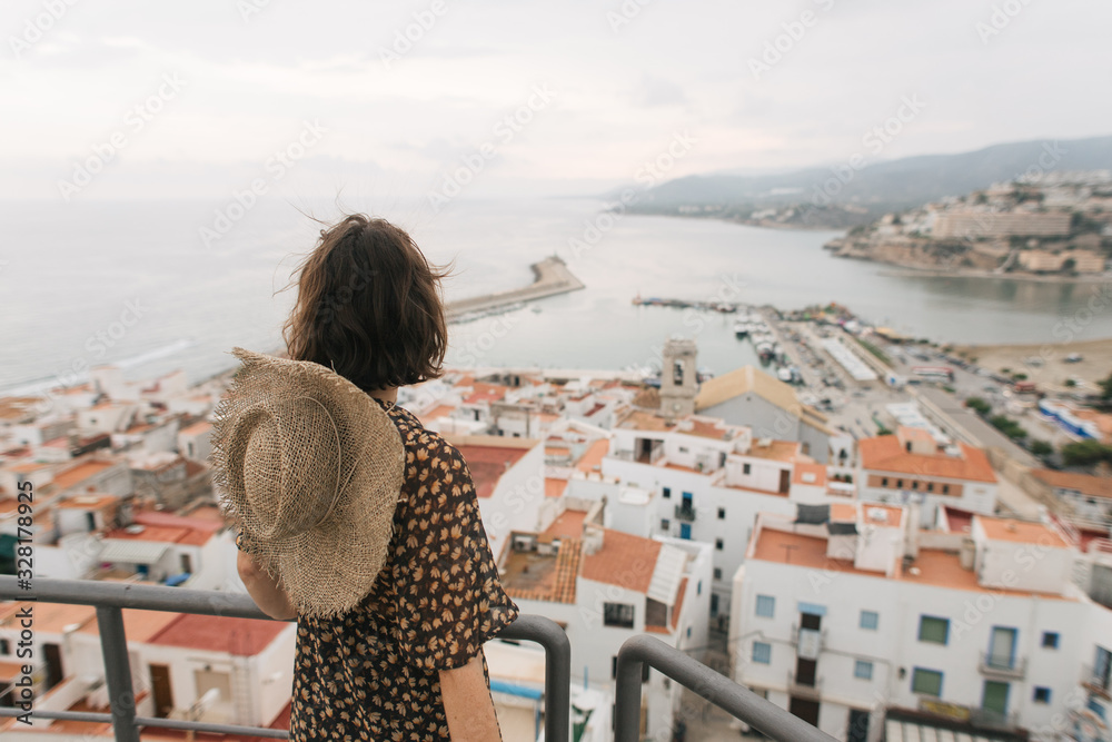 young female traveler stands on top of castle, city view, Peniscola Spain