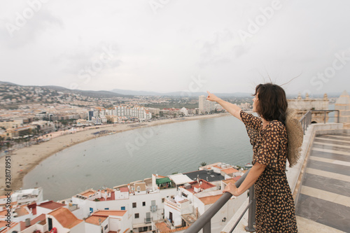 young female traveler stands on top of castle, city view, Peniscola Spain photo