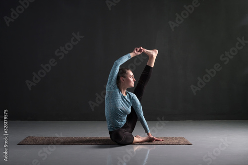 Sporty girl yoga workout, sitting in Heron pose, Krounchasana. photo