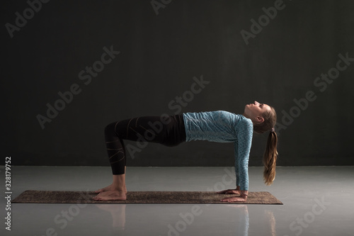 Woman practices yoga asana purvottanasana or upward facing plank photo