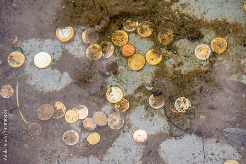 Coins at the bottom of a fountain seen through the magnification of the water deforming them