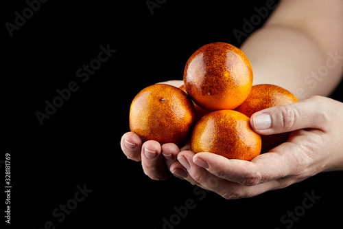 Hanful of whole red oranges on black background photo