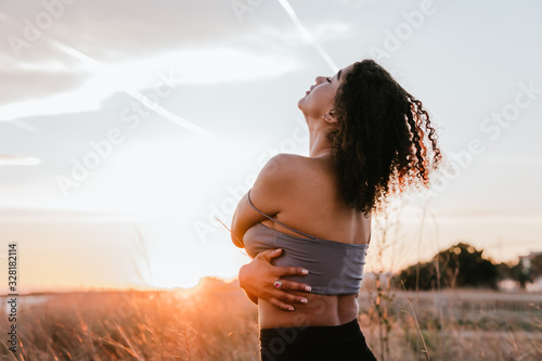 black girl hugging herself with the sky and the beach in the background