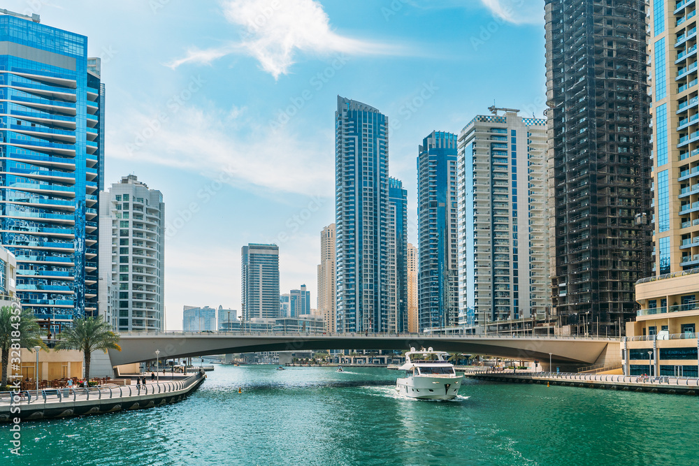 Fototapeta premium Luksusowy kanał Dubai Marina w letni dzień w Dubaju z wysokimi budynkami w tle, Zjednoczone Emiraty Arabskie.