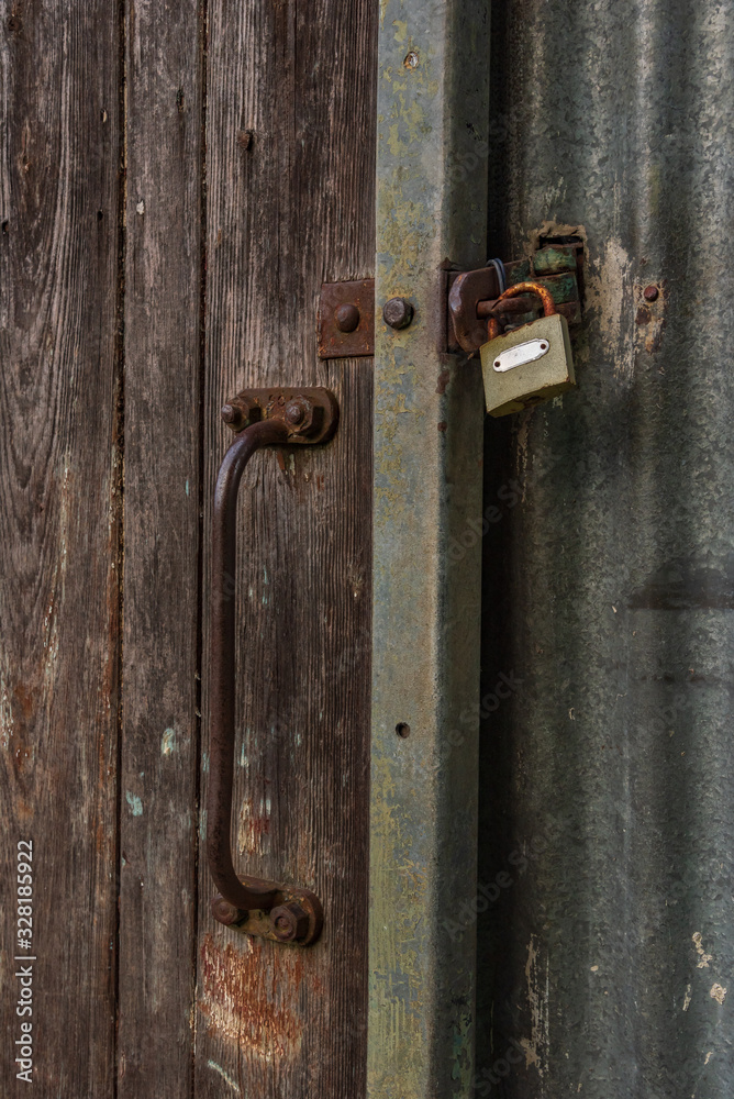 A wooden barn door closed with a padlock A wooden barn door closed with a padlock