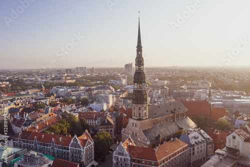 Aerial view photo from flying drone panoramic to St. Peter's Church and the Old Town on the background of the Daugava River and downtown on a beautiful early morning sunrise (series)