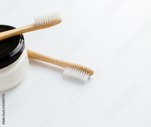 Two bamboo toothbrushes and natural toothpaste on plain white background isolated
