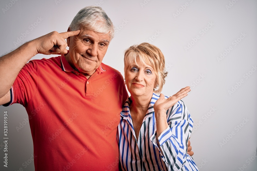 Senior beautiful couple standing together over isolated white background confused and annoyed with open palm showing copy space and pointing finger to forehead. Think about it. Senior beautiful couple standing together over isolated white background confused and annoyed with open palm showing copy space and pointing finger to forehead. Think about it.