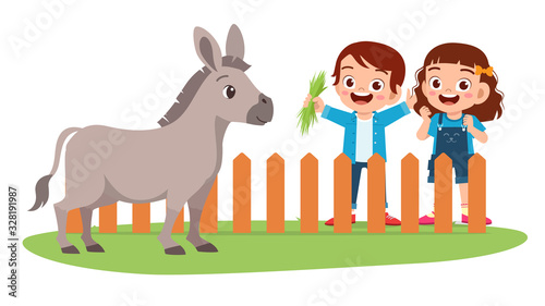 happy cute little kid boy and girl feed donkey
