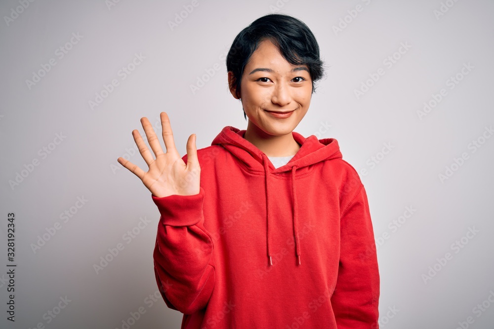 Young beautiful asian girl wearing casual sweatshirt with hoodie over white background showing and pointing up with fingers number five while smiling confident and happy. Young beautiful asian girl wearing casual sweatshirt with hoodie over white background showing and pointing up with fingers number five while smiling confident and happy.