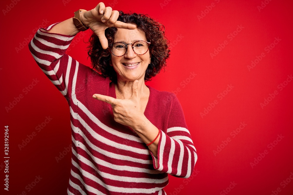 Middle age beautiful curly hair woman wearing casual striped sweater over red background smiling making frame with hands and fingers with happy face. Creativity and photography concept. Middle age beautiful curly hair woman wearing casual striped sweater over red background smiling making frame with hands and fingers with happy face. Creativity and photography concept.