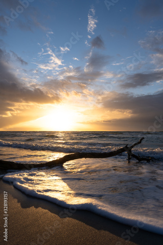 beautiful sunset over the sea  panorama view of a dramatic sunset with dark clouds. rain clouds or storm clouds before the storm  tree trunk lies in the water on the bea