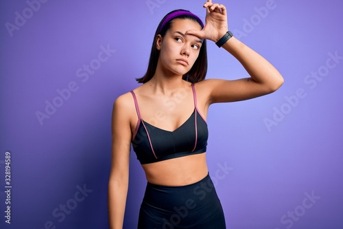 Young beautiful sporty girl doing sport wearing sportswear over isolated purple background making fun of people with fingers on forehead doing loser gesture mocking and insulting.