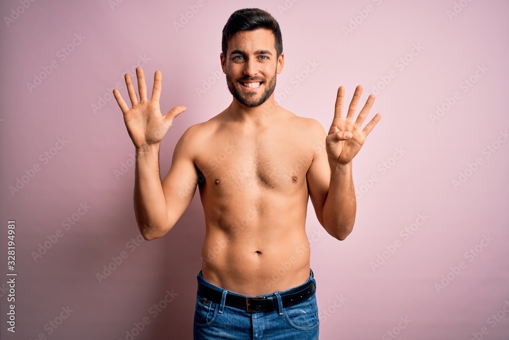 Young handsome strong man with beard shirtless standing over isolated pink background showing and pointing up with fingers number nine while smiling confident and happy.