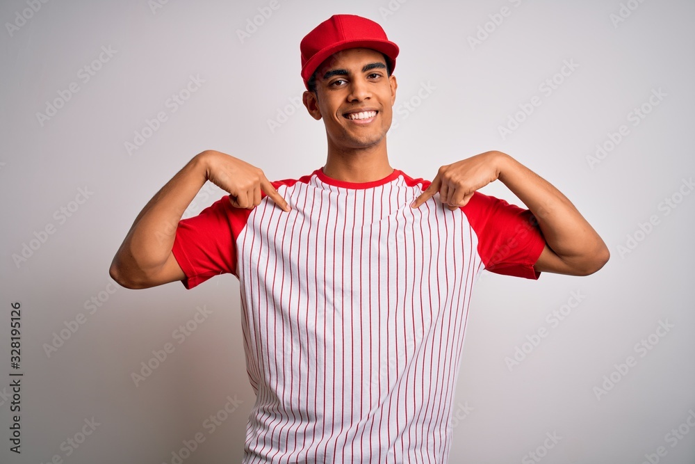 Young handsome african american sportsman wearing striped baseball t-shirt and cap looking confident with smile on face, pointing oneself with fingers proud and happy.