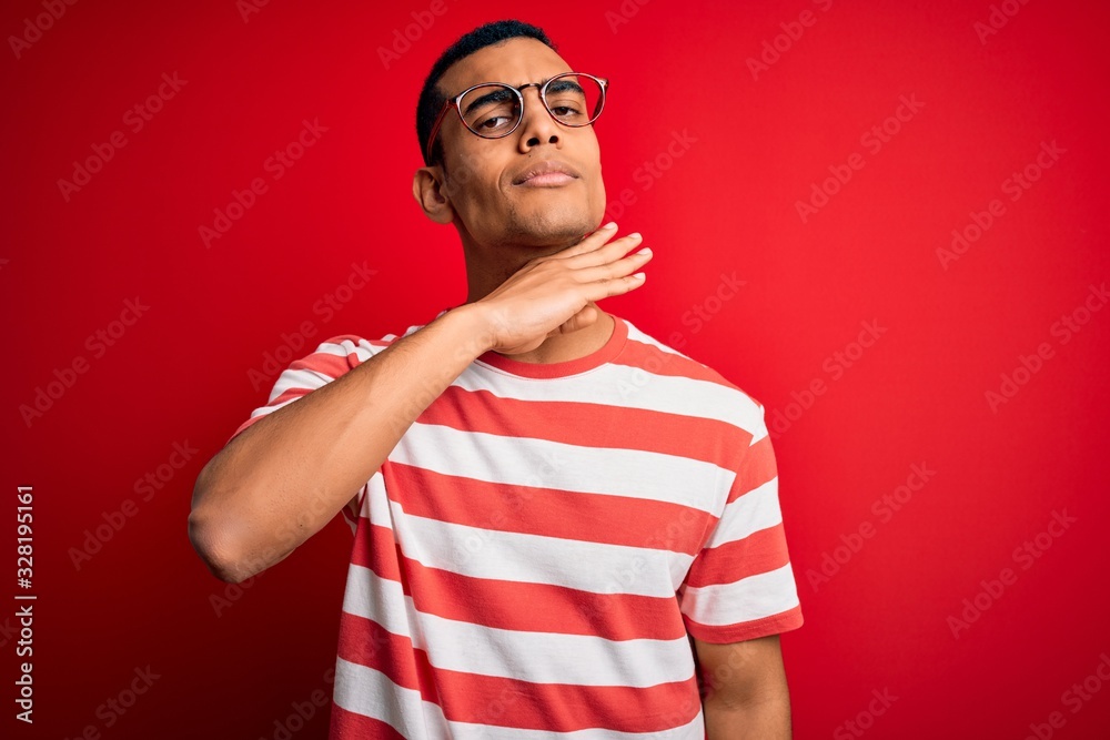 Young handsome african american man wearing casual striped t-shirt and glasses cutting throat with hand as knife, threaten aggression with furious violence Young handsome african american man wearing casual striped t-shirt and glasses cutting throat with hand as knife, threaten aggression with furious violence