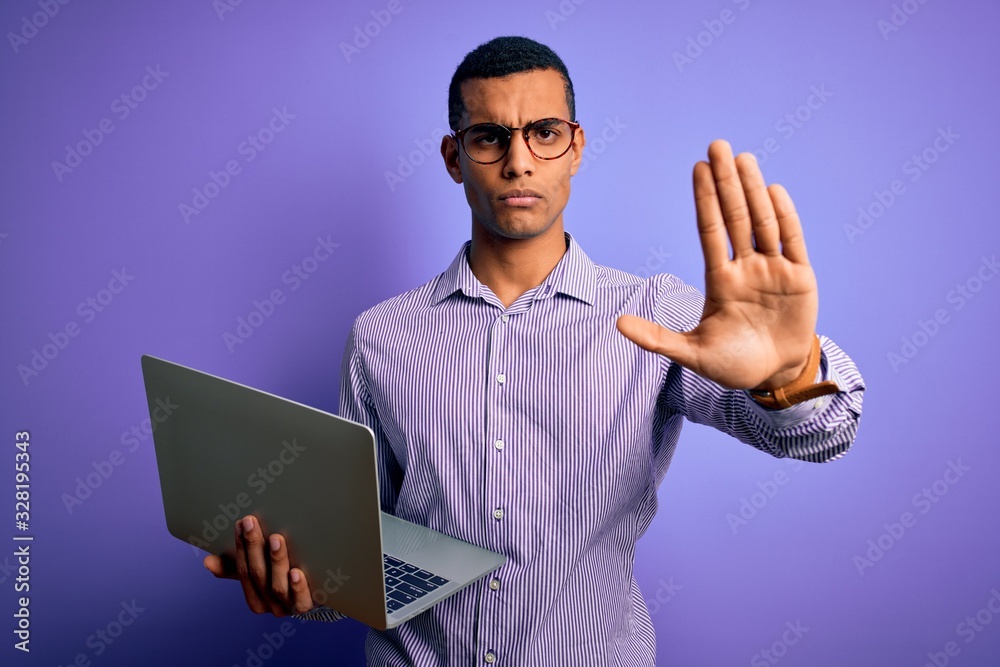 Young handsome african american business man working using laptop over purple background with open hand doing stop sign with serious and confident expression, defense gesture