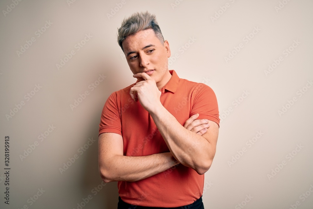 Young handsome modern man standing over isolated background with hand on chin thinking about question, pensive expression. Smiling with thoughtful face. Doubt concept. Young handsome modern man standing over isolated background with hand on chin thinking about question, pensive expression. Smiling with thoughtful face. Doubt concept.