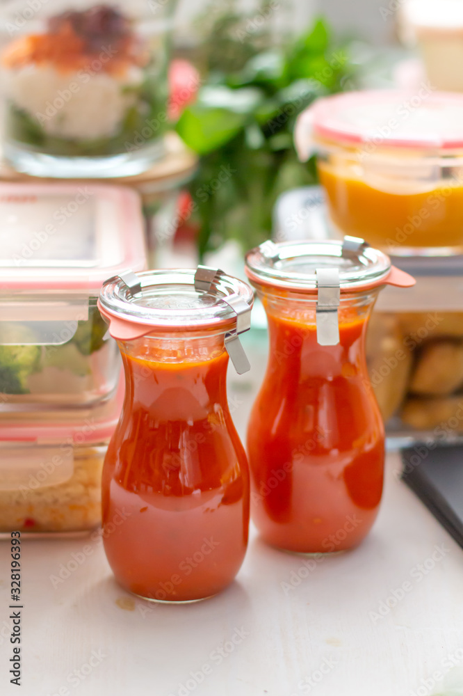 Closeup view of a couple of tomato sauce jars. Both metal top covers on them. In the back of the scene there are some glass jars full of healthy homemade meal. Closeup view of a couple of tomato sauce jars. Both metal top covers on them. In the back of the scene there are some glass jars full of healthy homemade meal.