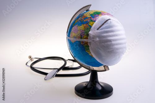 Protective surgical face mask on a terrestrial globe model. Coronavirus Concept. Surgical mask with rubber ear straps. Corona virus   nCoV  covid 19.  Coronavirus outbreak.