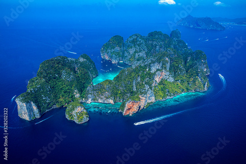 Top view of isolated rocky tropical island with turquoise water and white beach.