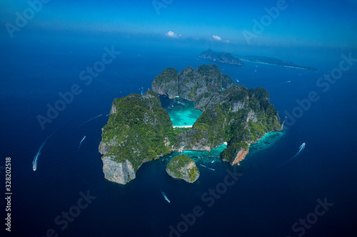 Top view of isolated rocky tropical island with turquoise water and white beach.