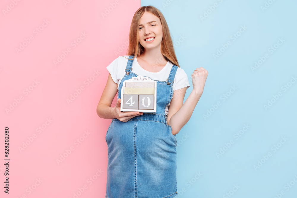 Attractive positive young beautiful pregnant woman posing holding a sign with a pregnancy period of 40 weeks Attractive positive young beautiful pregnant woman posing holding a sign with a pregnancy period of 40 weeks