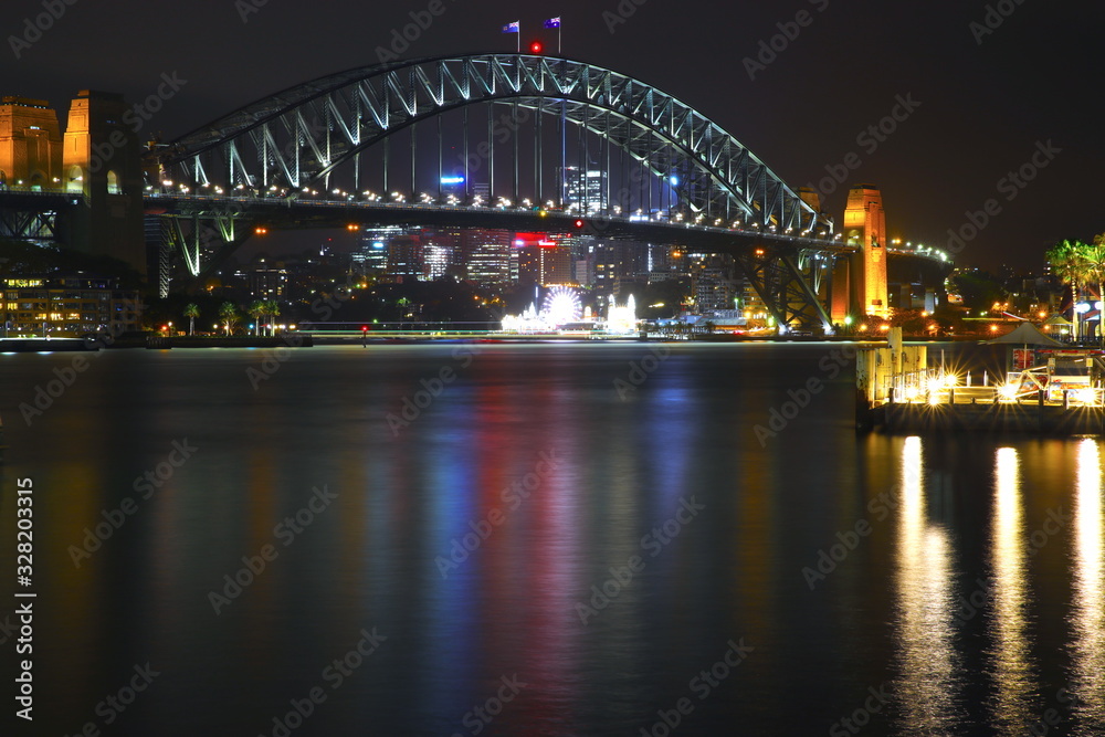 Sydney Harbour Bridge illuminating the harbour and circular quay with vibrant colourful lights at midnight in NSW Australia