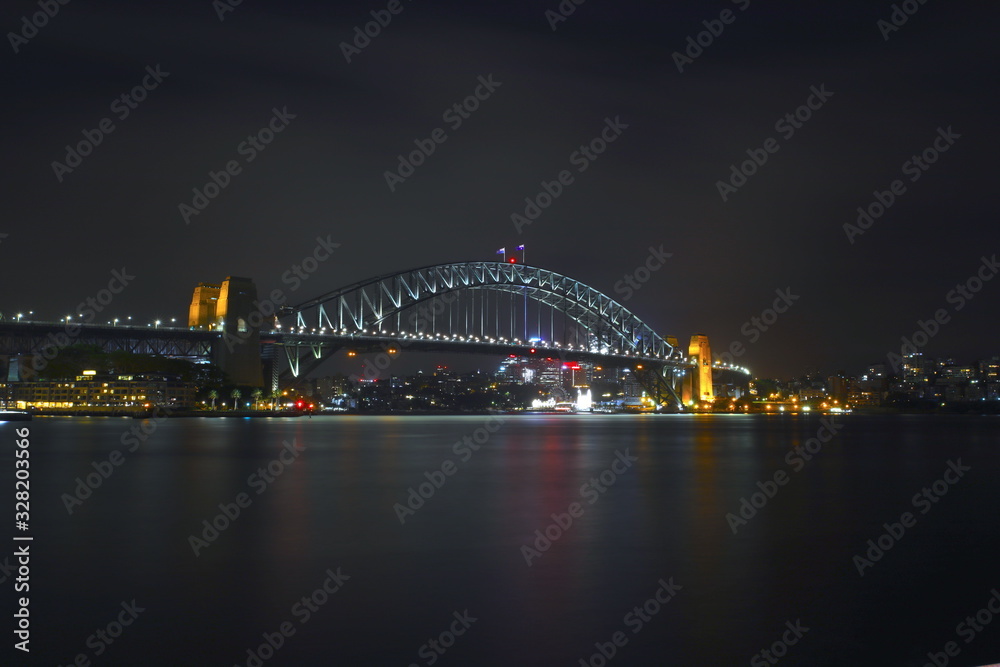 Sydney Harbour Bridge illuminating the harbour and circular quay with vibrant colourful lights at midnight in NSW Australia