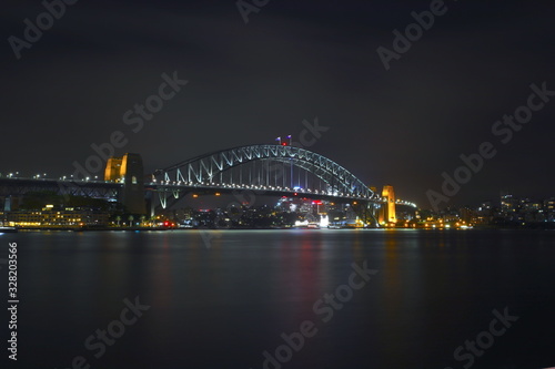 Sydney Harbour Bridge illuminating the harbour and circular quay with vibrant colourful lights at midnight in NSW Australia © Elias Bitar