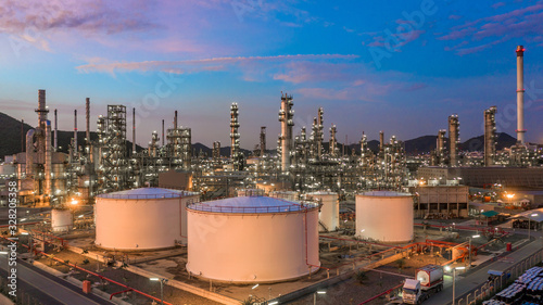 Oil​ refinery​ with oil storage tank and petrochemical​ plant industrial background at twilight, Aerial view oil and gas refinery at twilight.