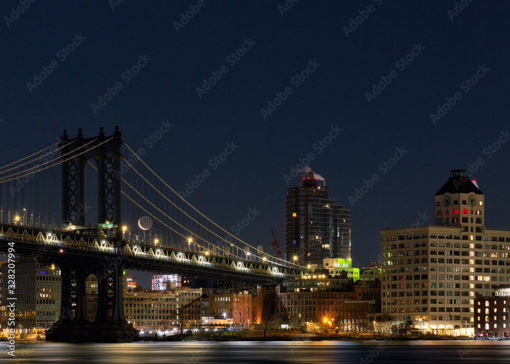 View on Dumbo neighborhood and Manhattan Bridge with waxing crescent moon at night