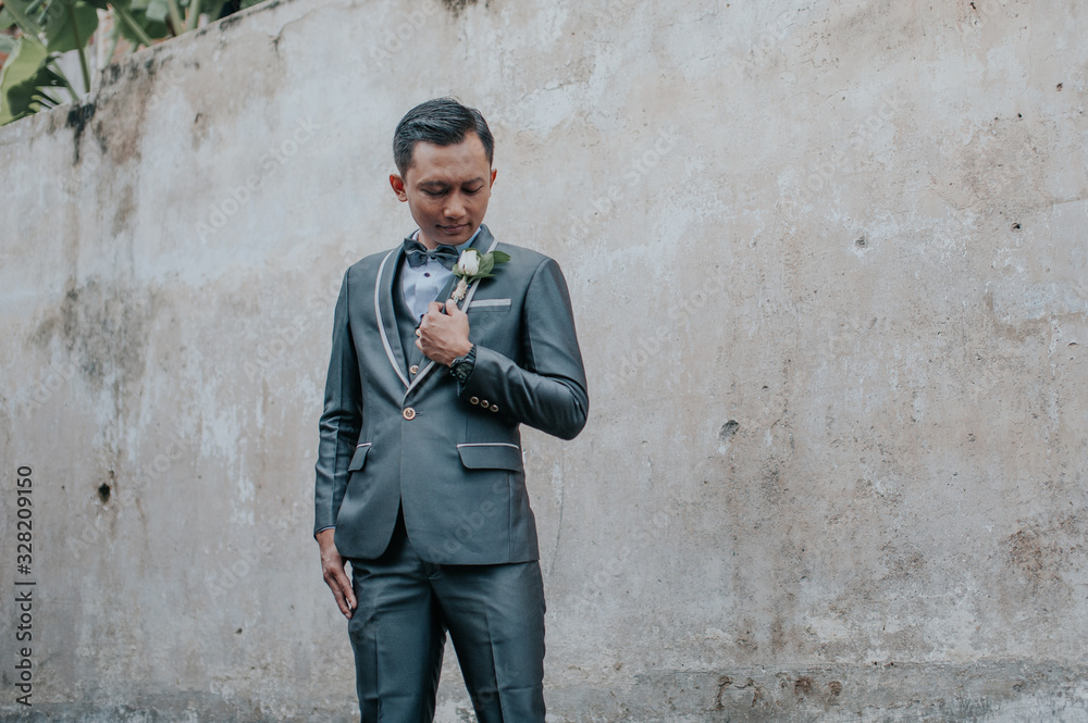 Selective focus of groom is standing with concrete wall background. Wedding concept. Selective focus of groom is standing with concrete wall background. Wedding concept.