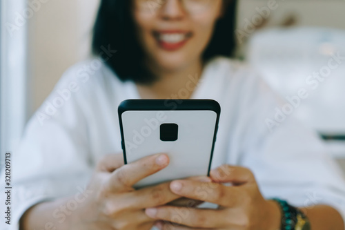 Woman feel happy and smile while using smartphone to do work business, social network, communication in public cafe work space.