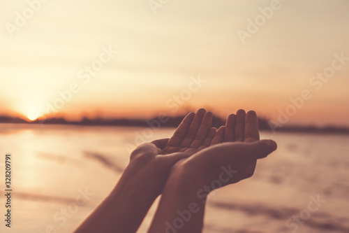Woman hands place together like praying in front of nature green  background.